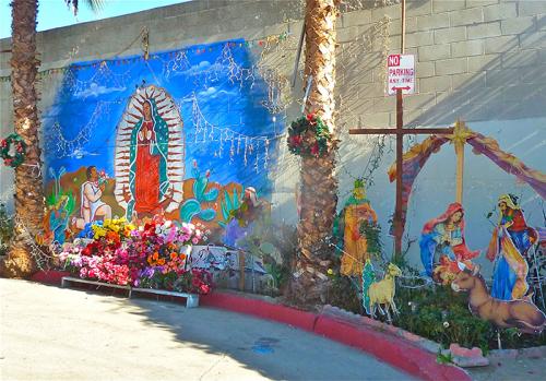 A mural and altar honoring la Virgen de Guadalupe and a nacimiento are installed on a dead-end street wall created by a one of several freeways that cut through the neighborhood of Boyle Heights.