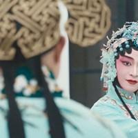 Two people dance in sky blue Chinese robes facing each other.
