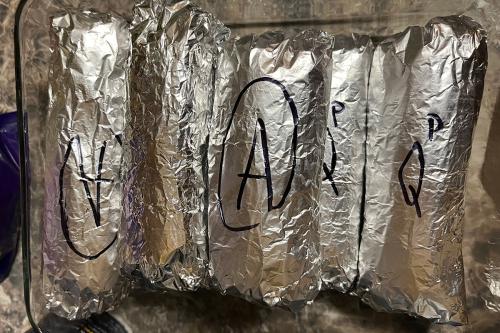 Five humitas wrapped in tin foil and labels in black Sharpie with A or Q.