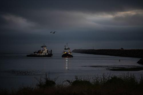 Two fishing boats near a shoreline at dusk.