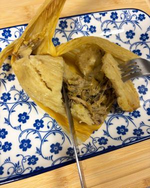 Close-up on the humita, cut open to reveal brown shredded meat.
