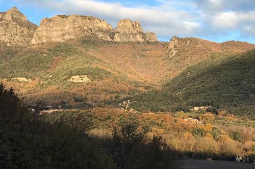 Sunlit mountain, with roofs of homes and a bell tower peaking through the trees.
