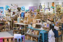 Bright interior of a store chock full of art and craft items on blonde wood shelving.