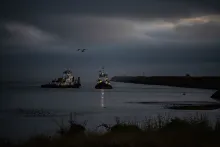 Two fishing boats near a shoreline at dusk.