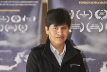 A man poses in front of two identical movie posters.